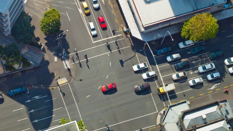An aerial view of a city intersection with cars and people.