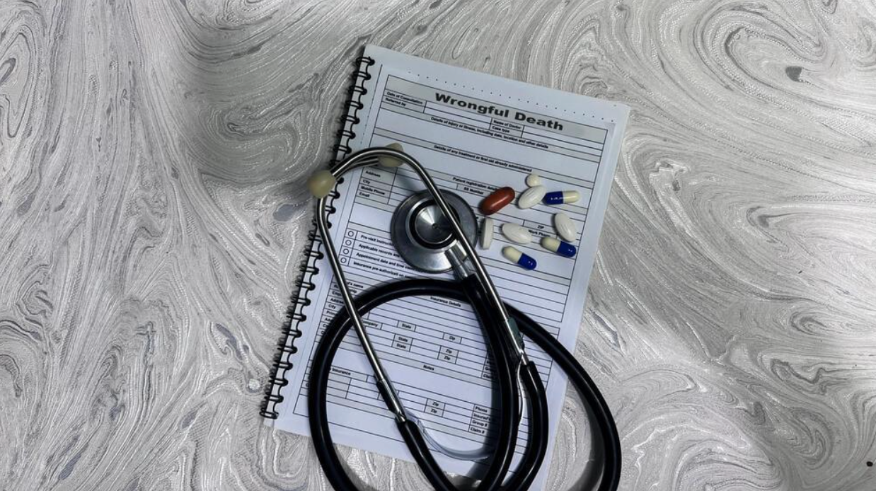 A stethoscope is sitting on top of a notebook with pills on it.