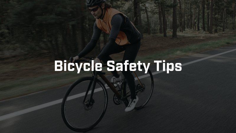 A cyclist rides on a paved road through a forest with the text
