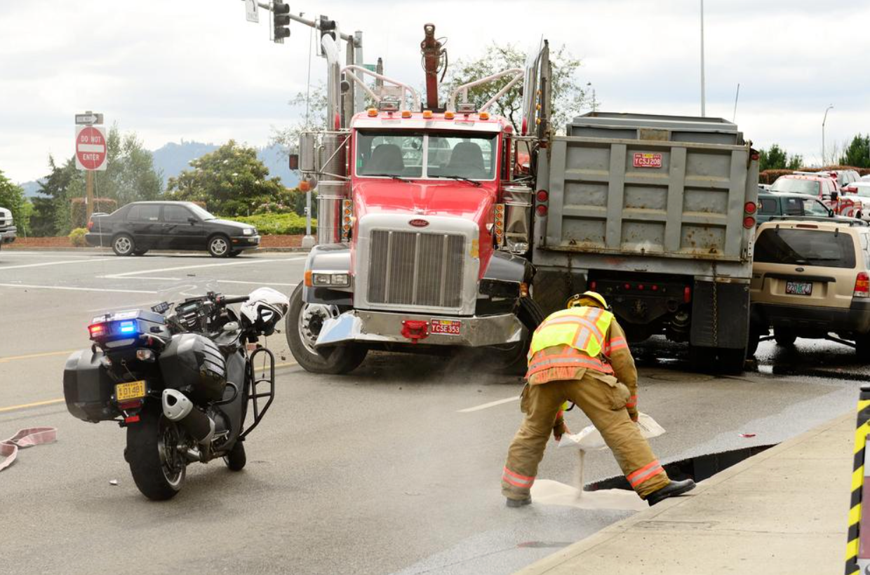 A motorcycle is parked next to a fireman and a dump truck