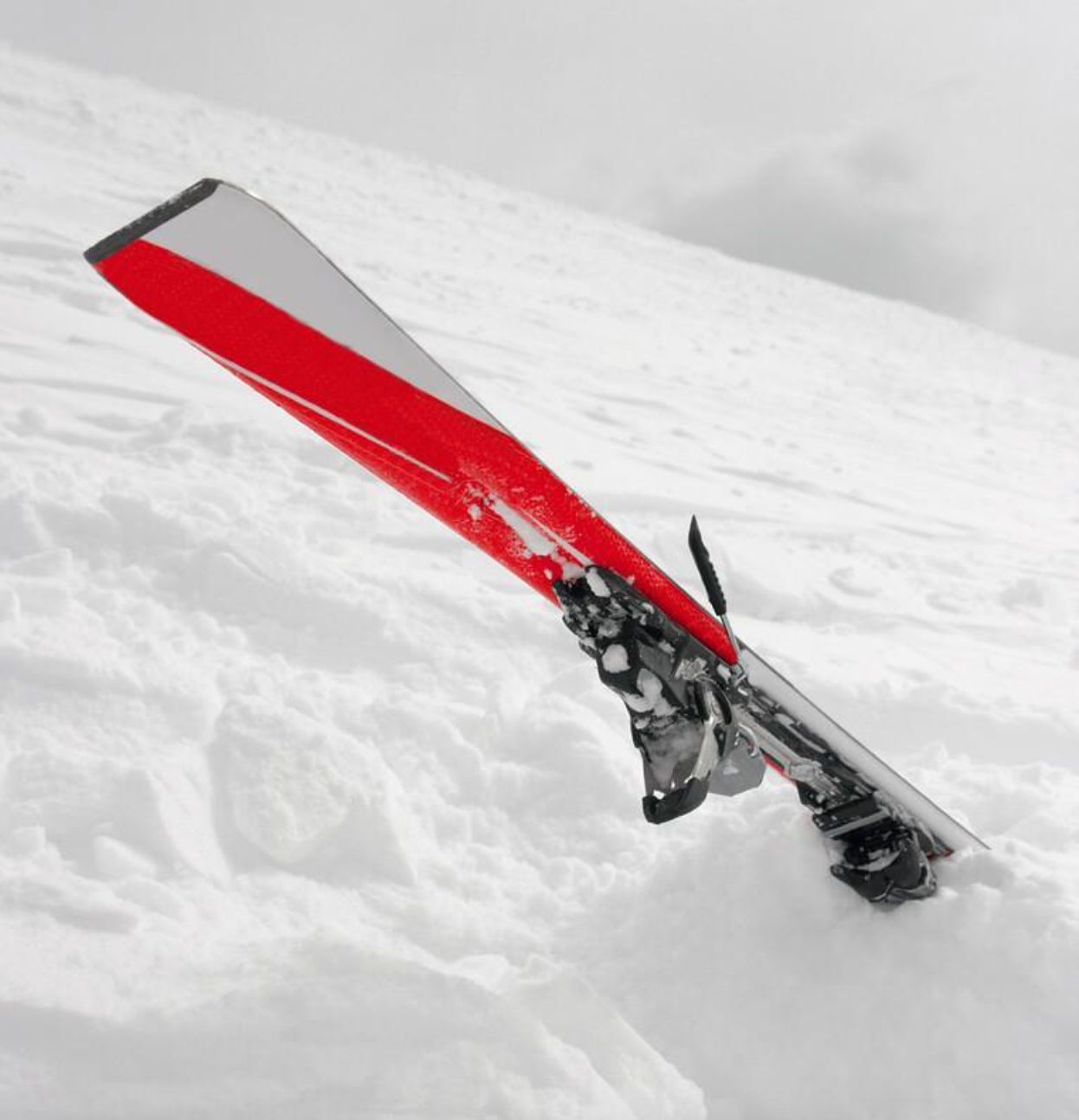 A red and white ski is laying in the snow