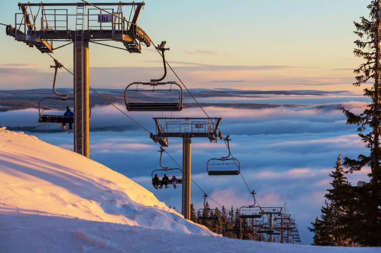 A ski lift is going up a snow covered mountain.