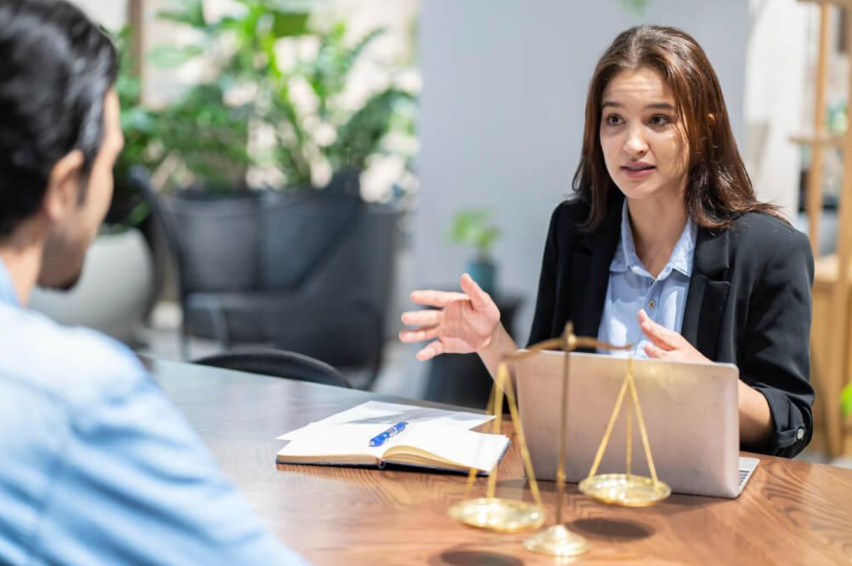 A woman is sitting at a table talking to a man.
