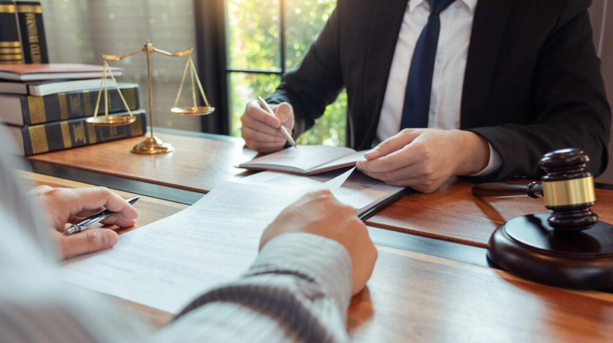 A lawyer is sitting at a desk talking to a client.