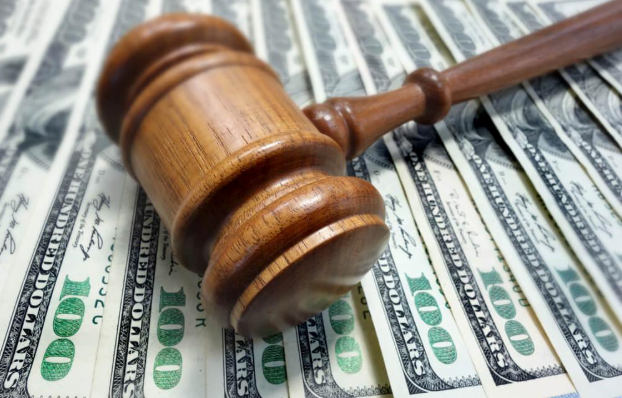 A wooden judge 's gavel is sitting on top of a pile of 100 dollar bills