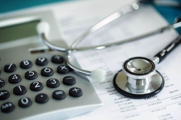 A stethoscope is sitting on top of a calculator on a piece of paper.
