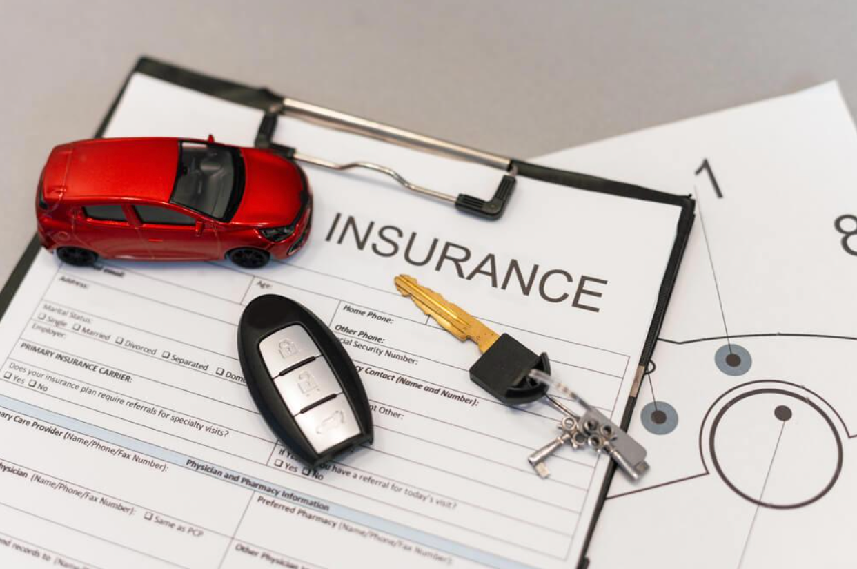 A red toy car is sitting on top of an insurance form.