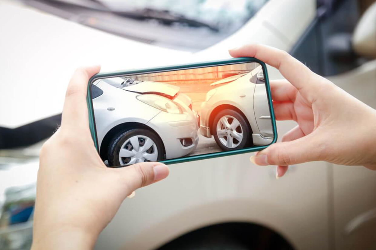 A person is taking a picture of a car accident with a cell phone.