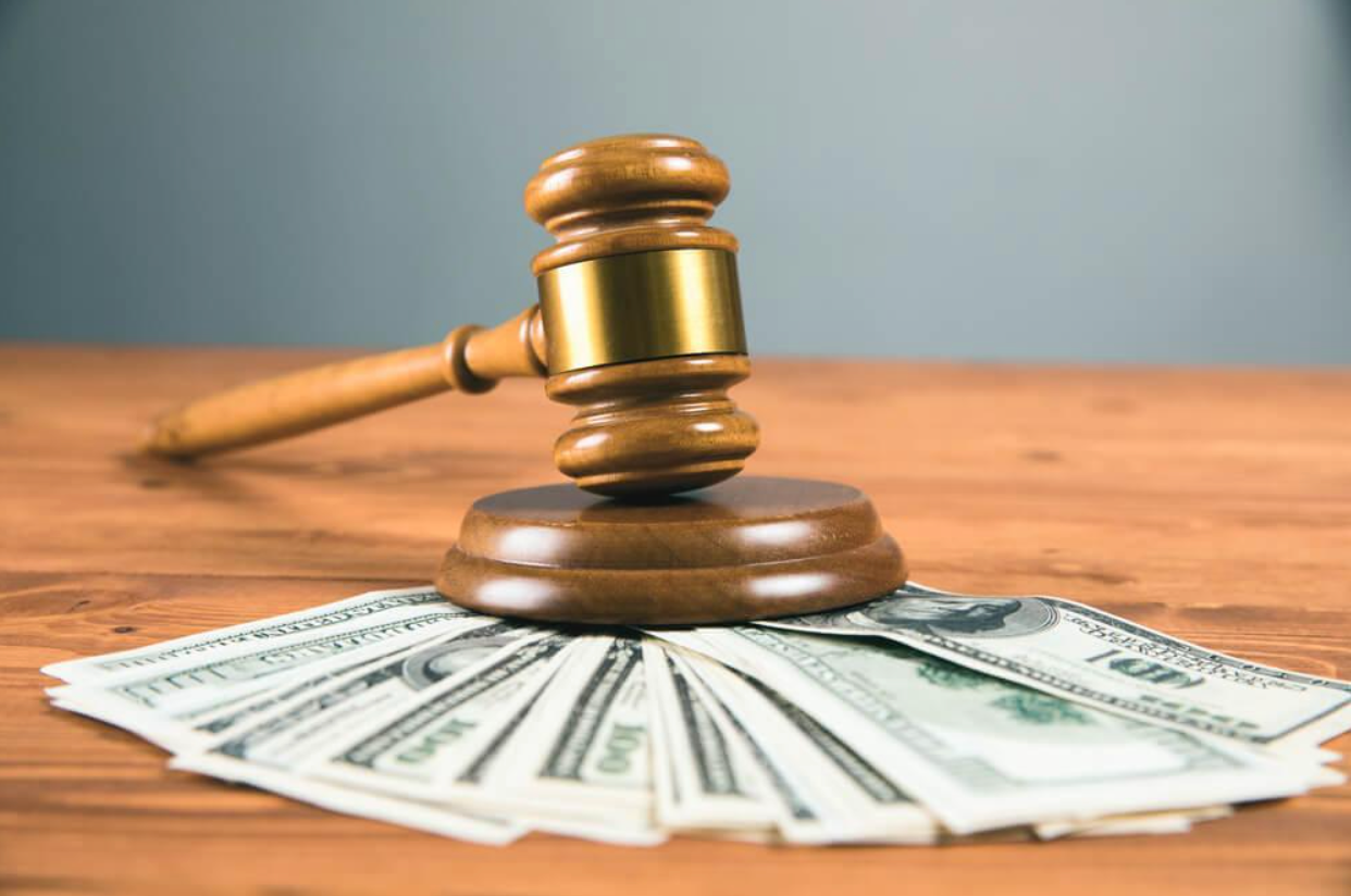 A wooden judge 's gavel is sitting on top of a pile of money on a wooden table.