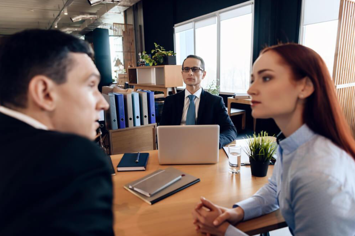 A man and a woman are sitting at a table with a laptop.