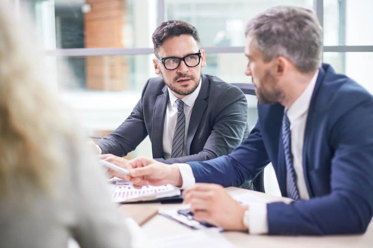 A group of businessmen are sitting at a table having a meeting.