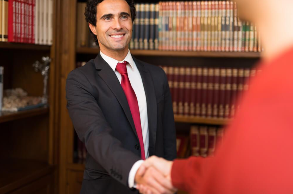 A man in a suit and tie is shaking hands with another man.