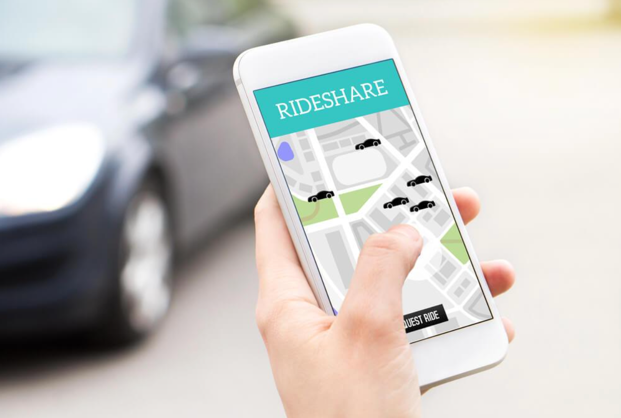 A person is holding a cell phone with a rideshare app on it.