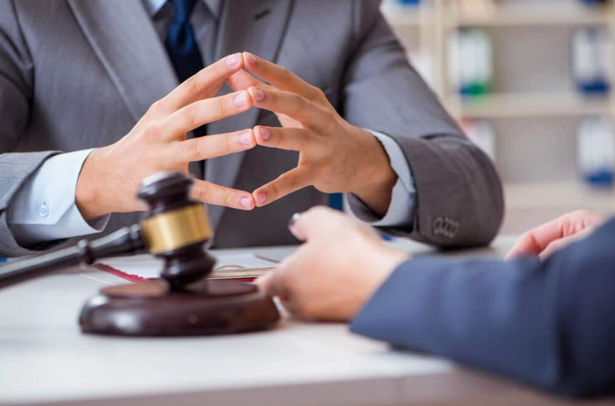 A man in a suit and tie is sitting at a table with a judge 's gavel.