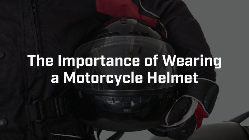 A person in a black riding jacket holds a black motorcycle helmet, with the text