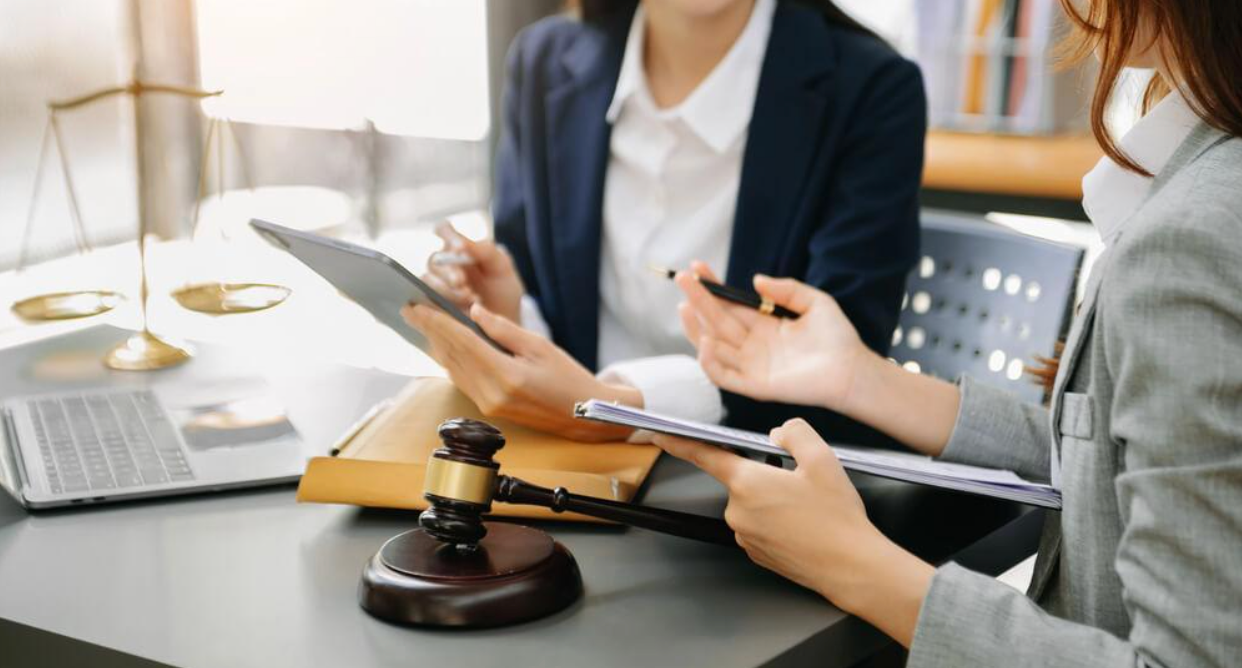 Two women are sitting at a table looking at a tablet.