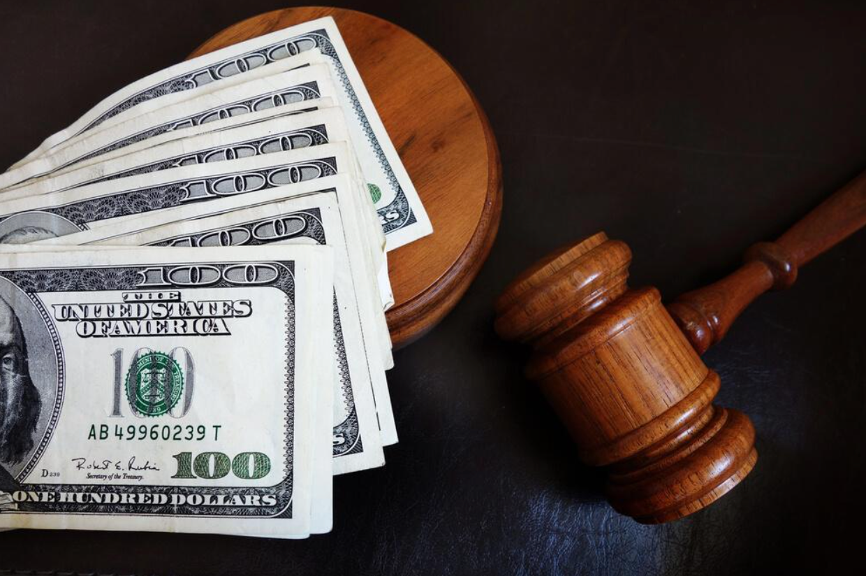 A stack of 100 dollar bills next to a judge 's gavel