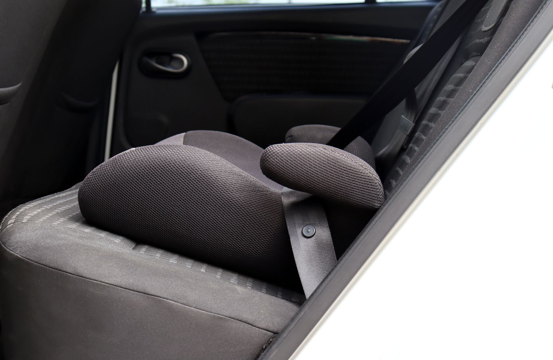 Rear car seat with a black headrest cushion and seatbelt.