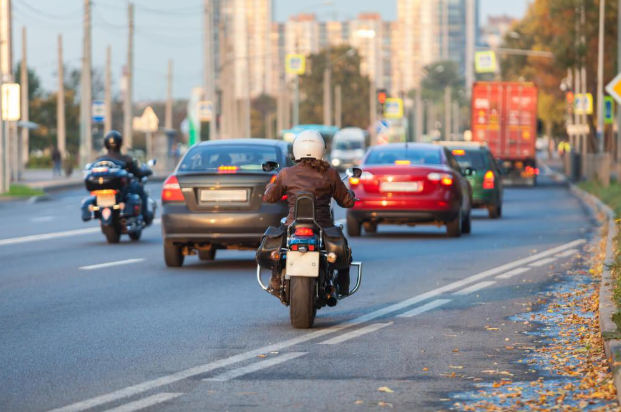 A man is riding a motorcycle down a city street.