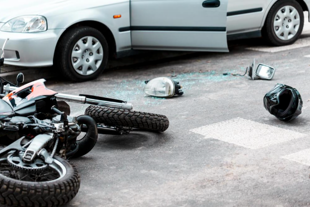 A motorcycle is laying on the ground next to a car.