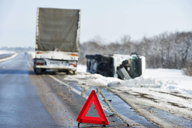 A red triangle is sitting on the side of the road next to a truck.