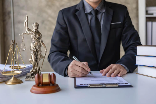 A lawyer is sitting at a desk writing on a clipboard.