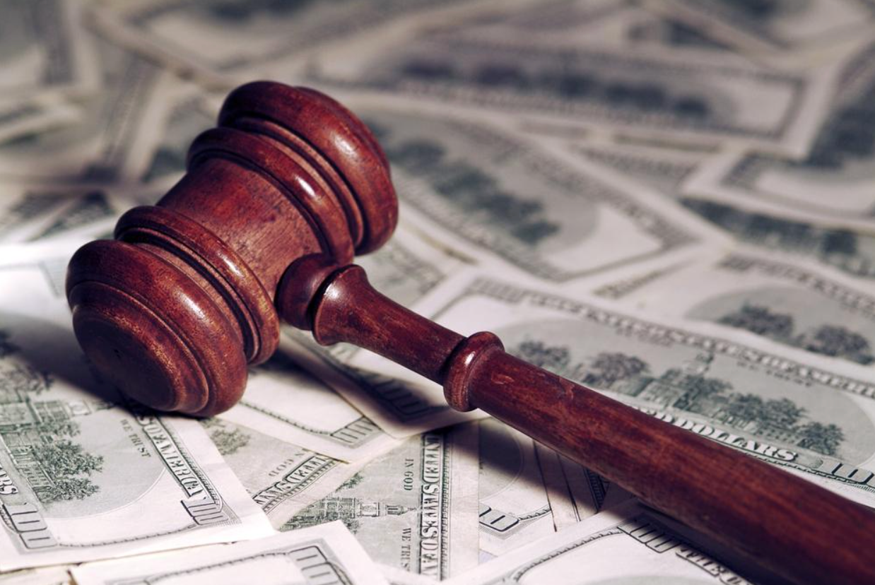 A wooden judge 's gavel is sitting on top of a pile of money.