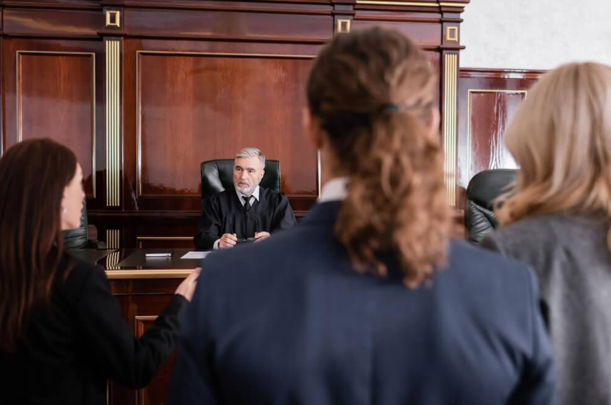 A group of people are standing in front of a judge in a courtroom.