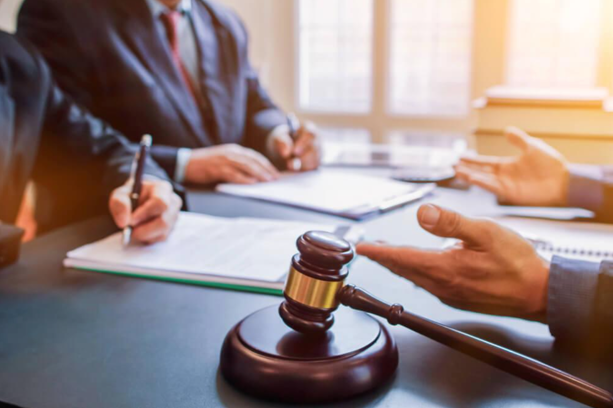 A group of people are sitting at a table with papers and a judge 's gavel.