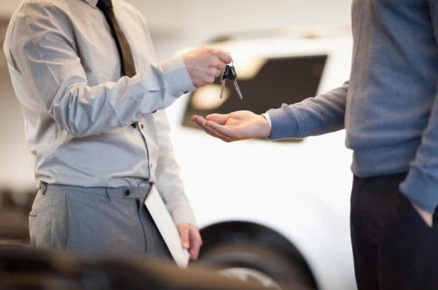 A man is handing a car key to another man