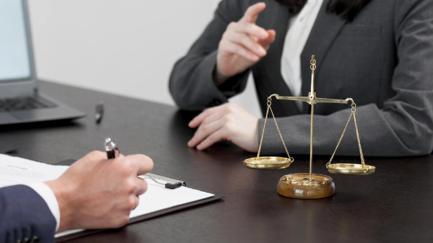 A man and a woman are sitting at a table with scales of justice.