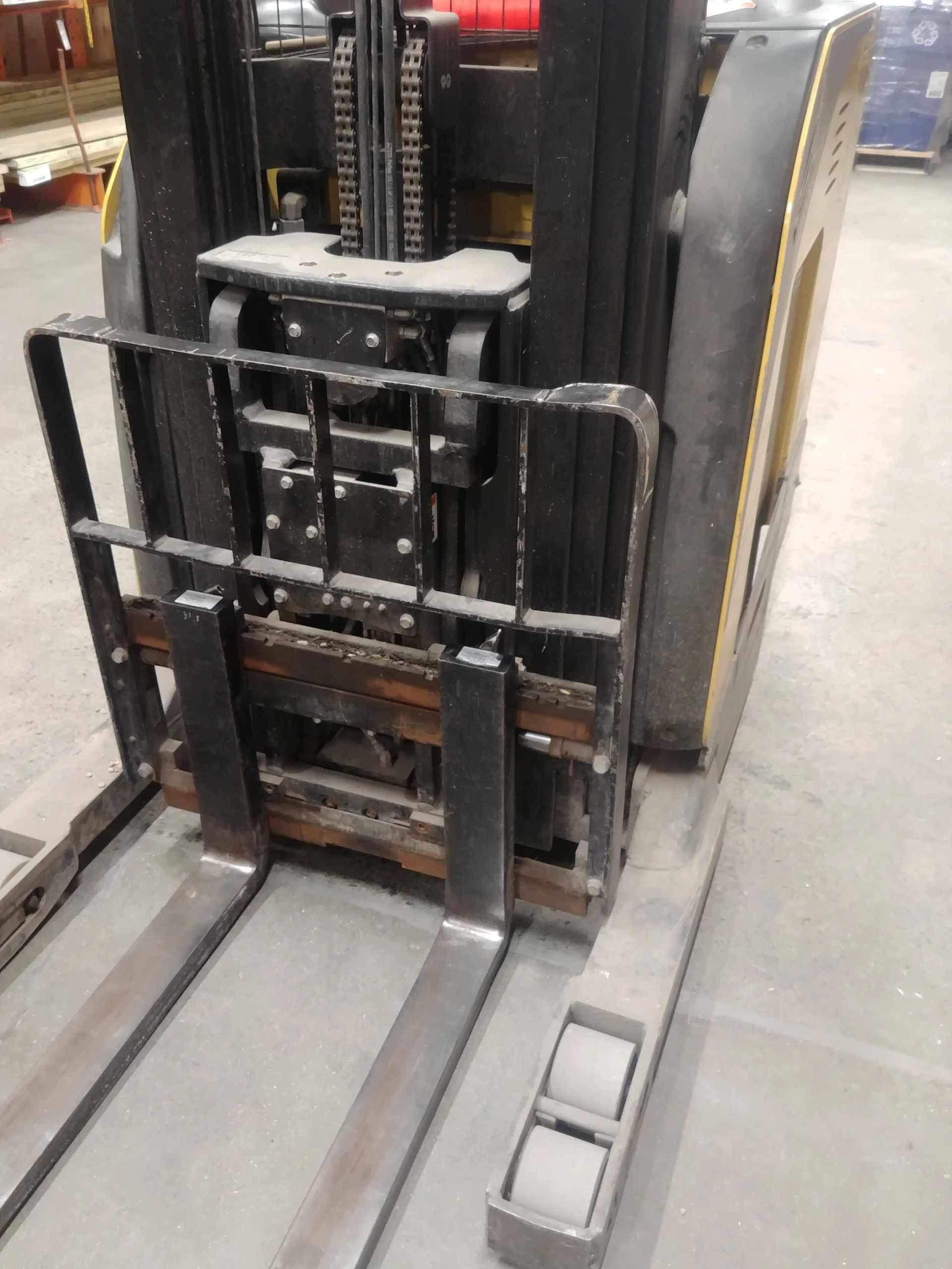 Forklift with steel forks and black frame, indoors.
