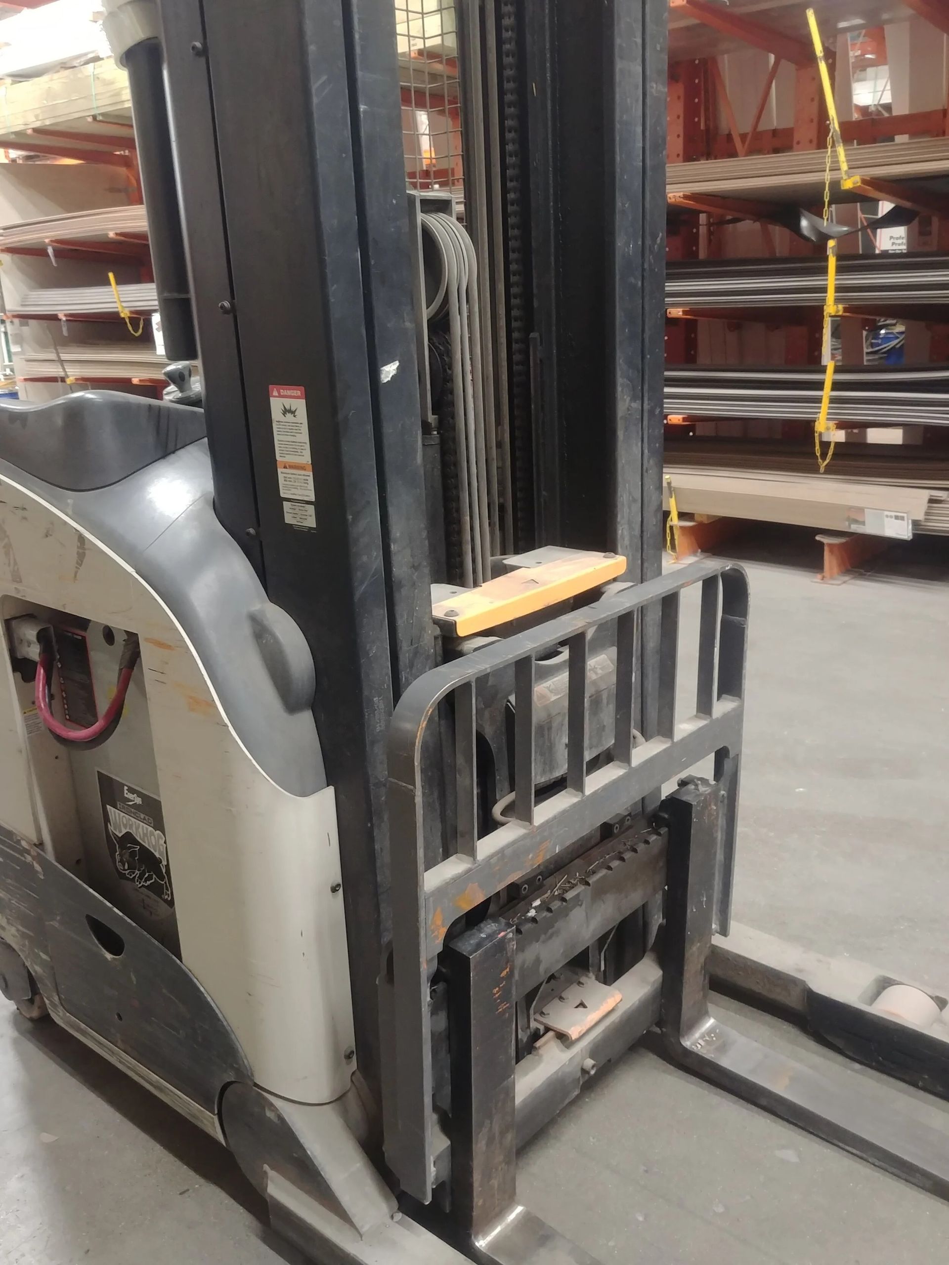 Side view of an industrial forklift with extended forks, in a warehouse setting.