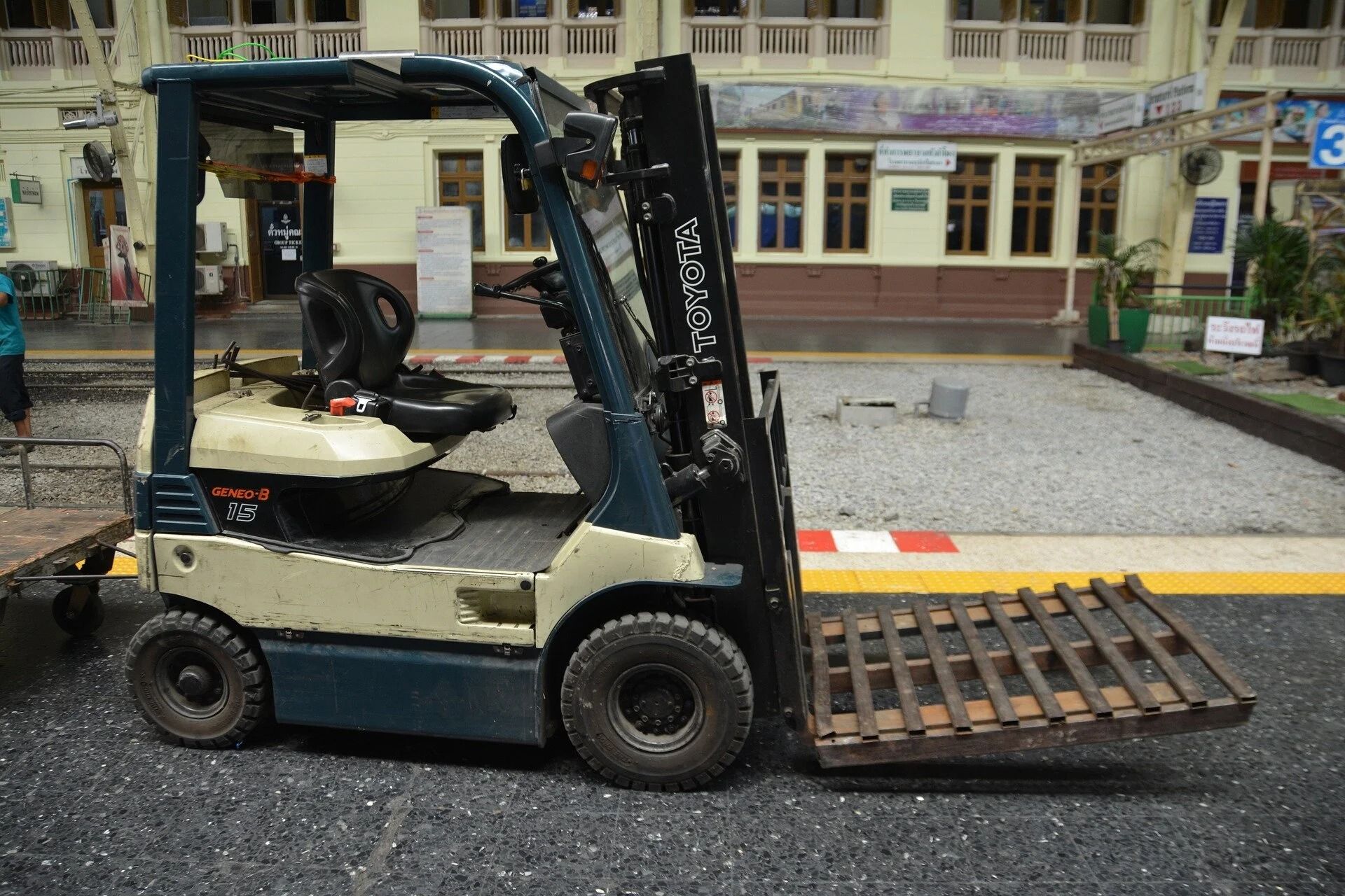 Forklift on gravel, with building in the background.