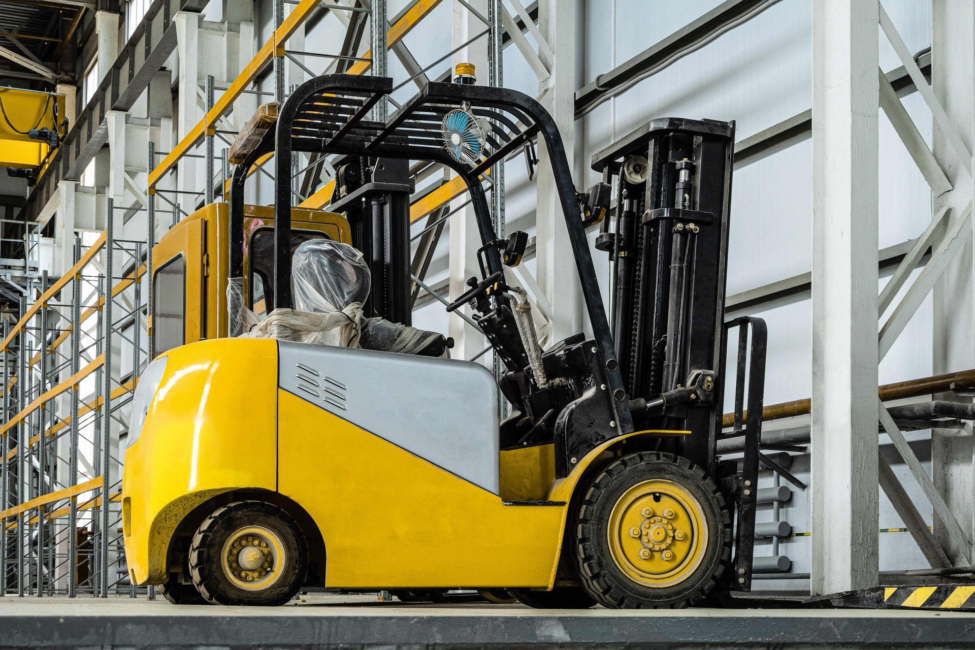 Yellow and gray forklift in an industrial warehouse.
