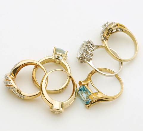 Anelli d’oro assortiti con diamanti e pietre preziose colorate su sfondo bianco