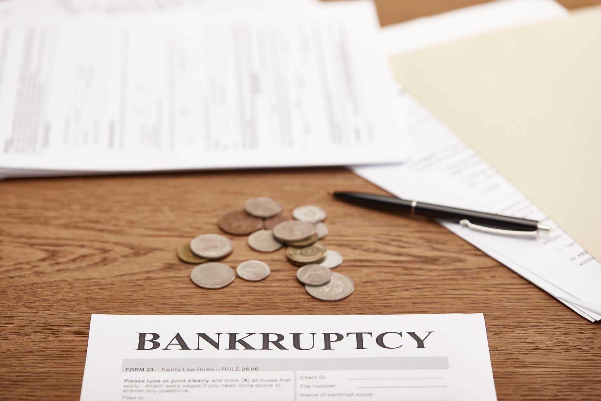 Bankruptcy document on desk with scattered coins and pen, symbolizing financial distress