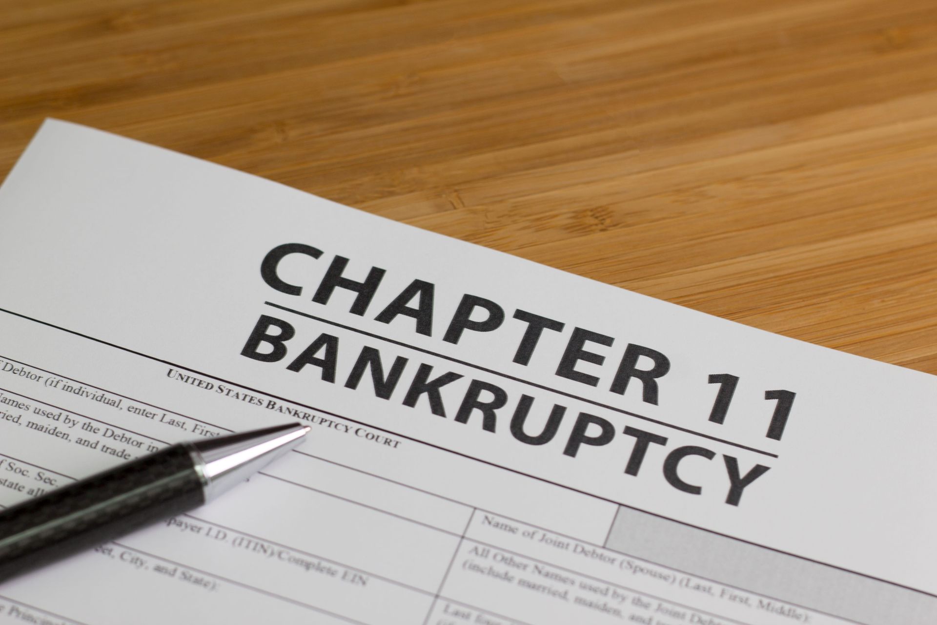 Chapter 11 bankruptcy form with pen on a wooden desk