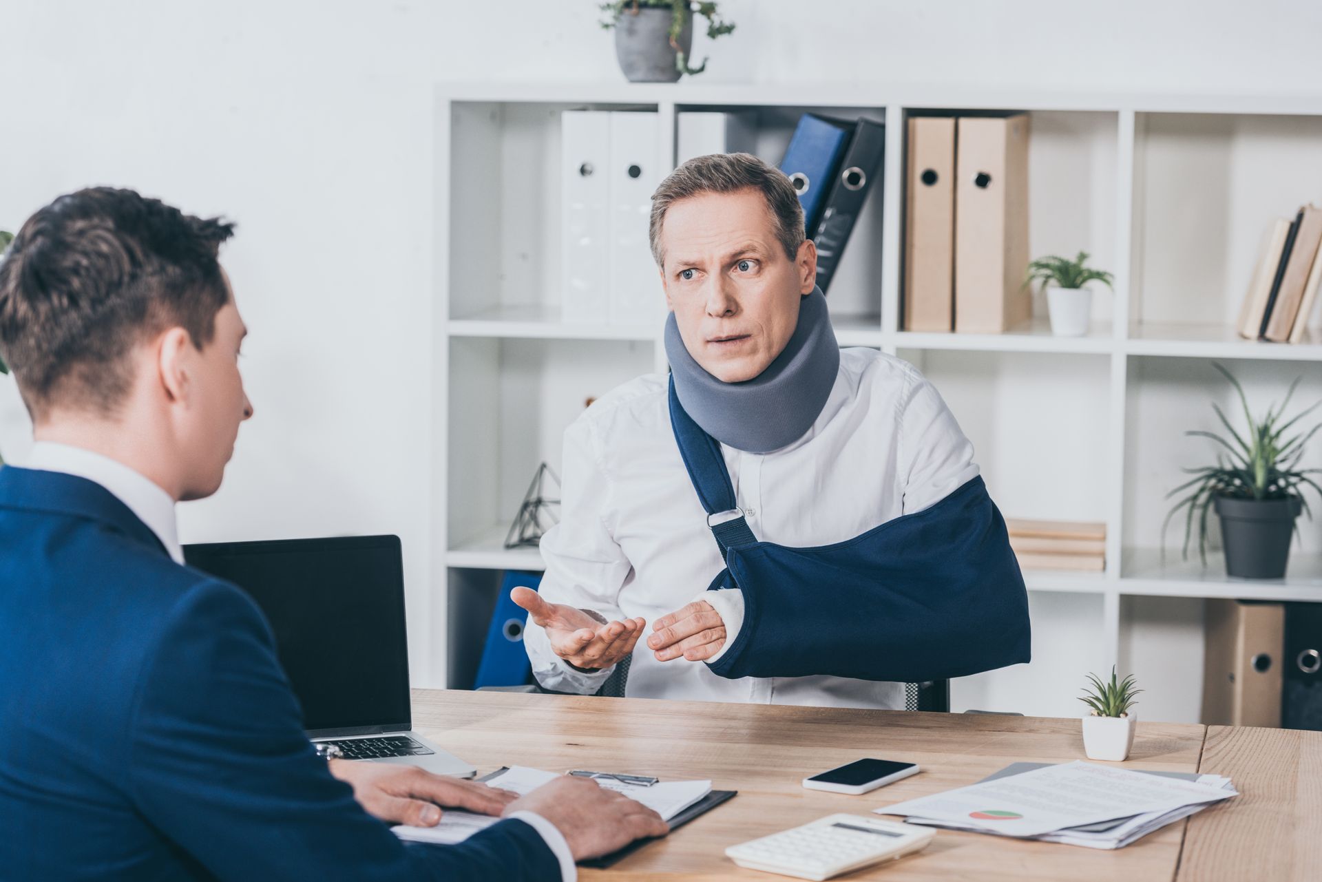 Two people in a bright office discussing paperwork across a desk