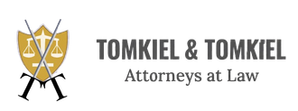 Tomkiel & Tomkiel Attorneys at Law logo with gold scales and black text