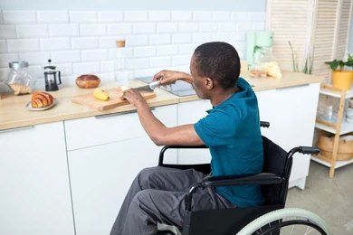 Person in Wheelchair Slicing Food on a Kitchen Counter — My Coast Projects in West Gosford, NSW