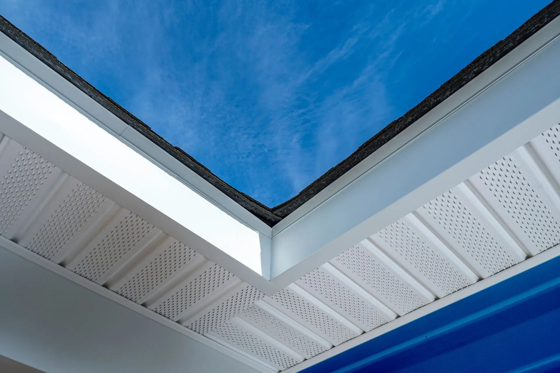 Corner of a white building roof against a bright blue sky
