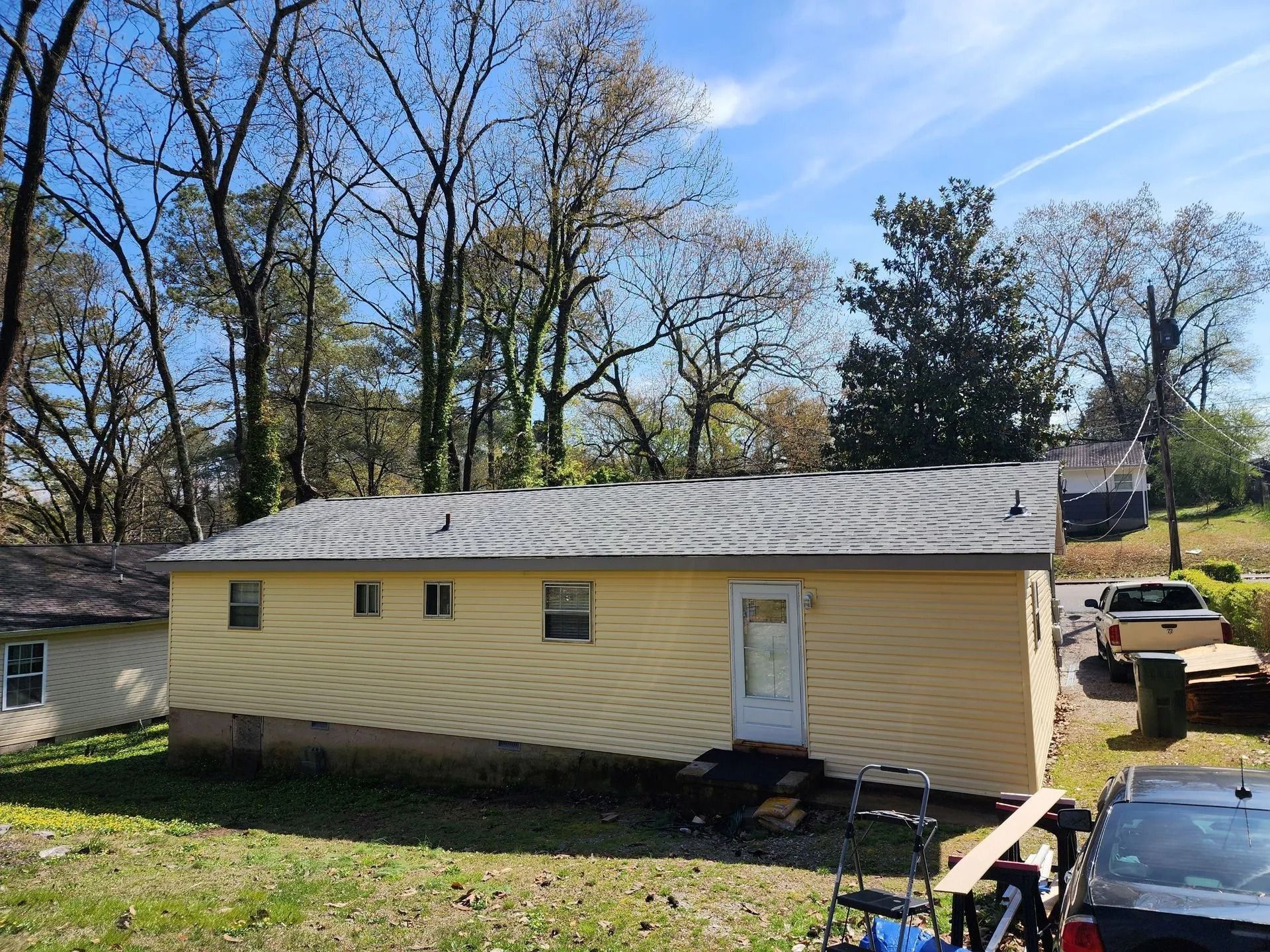 A single-story, light yellow house with a brick-covered lower exterior and a 