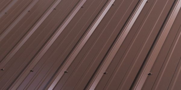 Brown corrugated metal roof with evenly spaced pale ridges and fasteners