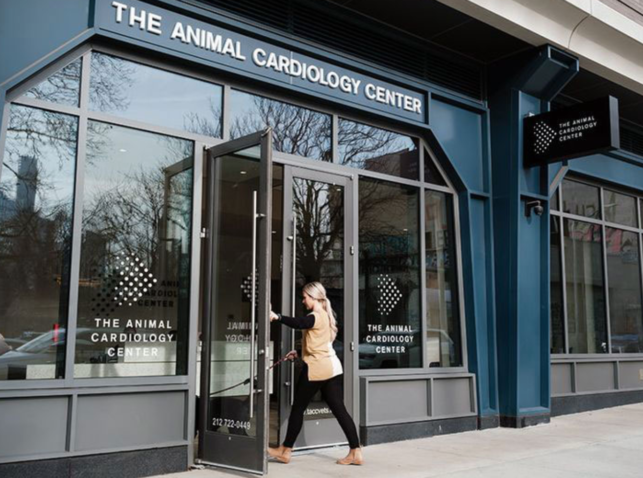 a woman is walking into the doorway of the animal cardiology center .