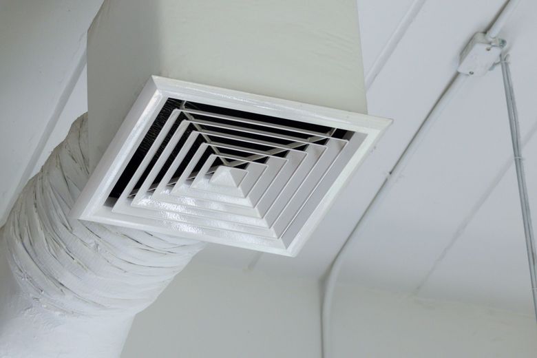 A close up of an air vent on the ceiling of a building.