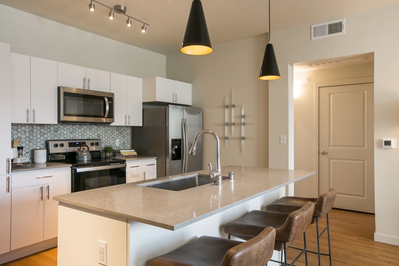 Modern kitchen with white cabinets, stainless appliances, and an island with a sink.