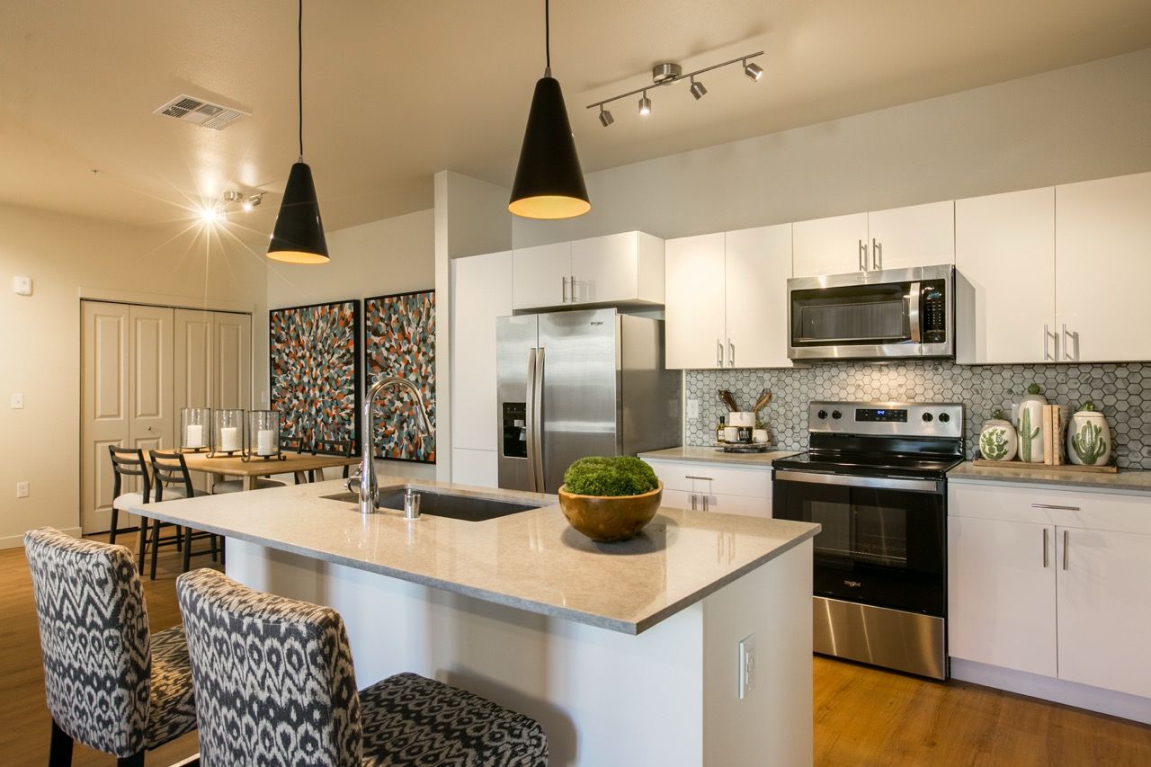 Modern kitchen with white cabinets, stainless steel appliances, and a large island.