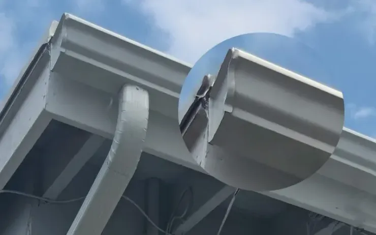 Close-up of two gray satellite dishes mounted under a metal roof against a blue sky