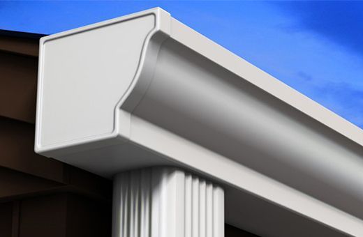 White gutter and downspout on a house roof against a blue sky
